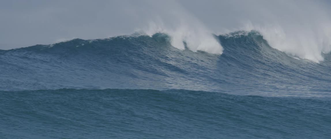 A tall wave falls in the ocean