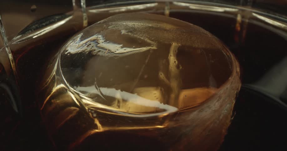 Wrapped object bobs in reflective brown beverage filling container