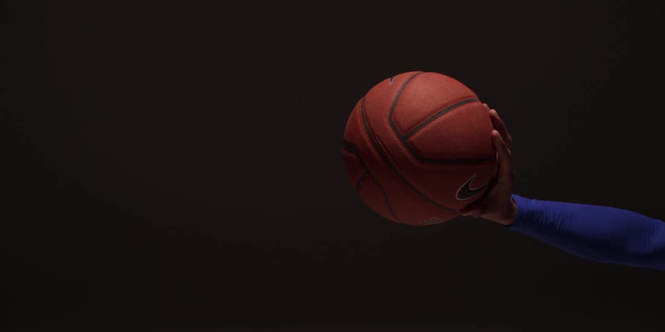 Person wearing long sleeve throws basketball in dark area