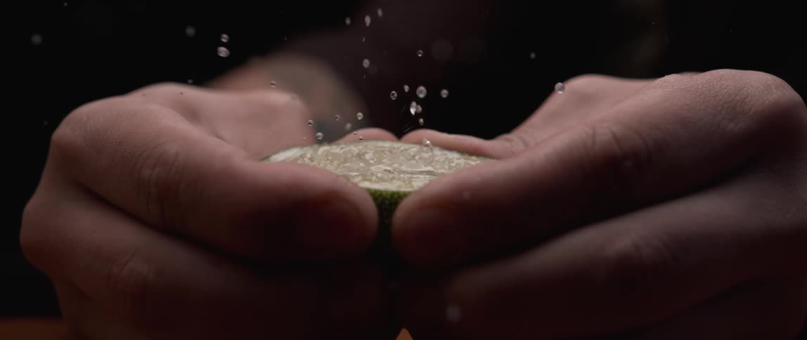 A person squeezing a lime in a room