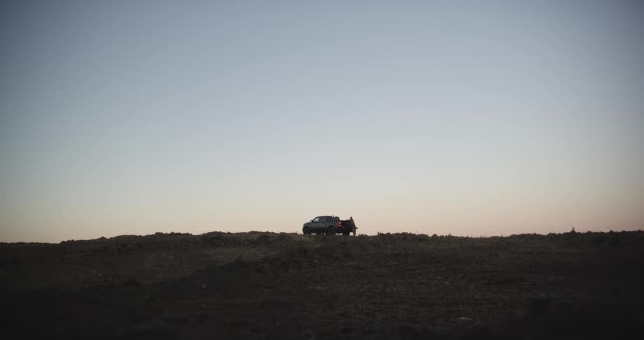 A man walking to the back of a truck parked in a field