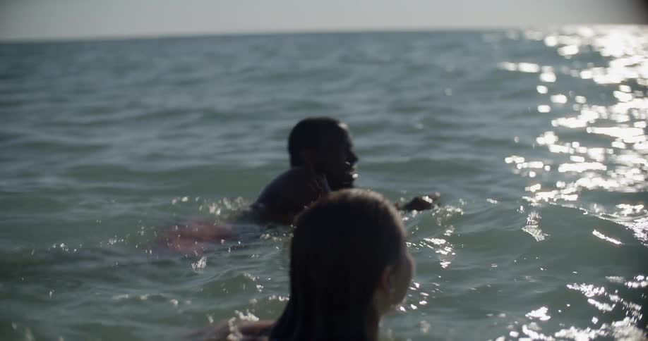 A man and woman swim in a body of water during the day