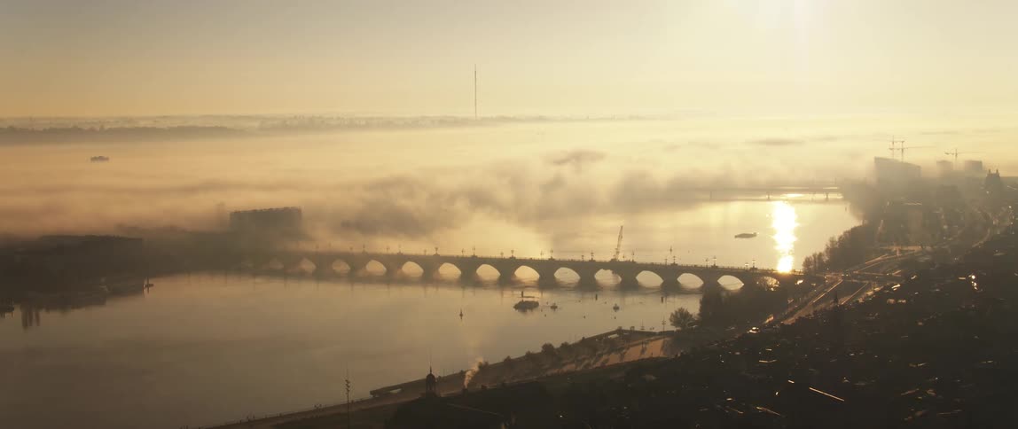 A boat sails past a bridge that connects to a city