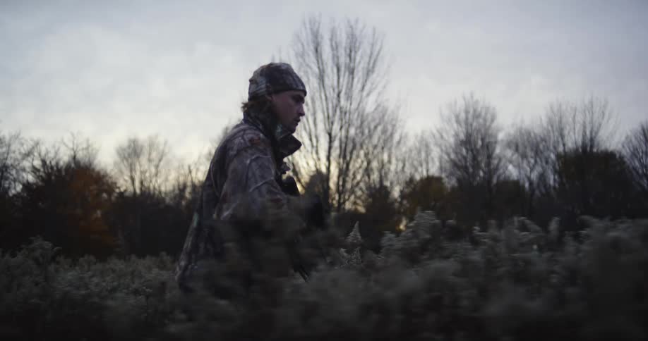 A hunter stops and aims his crossbow