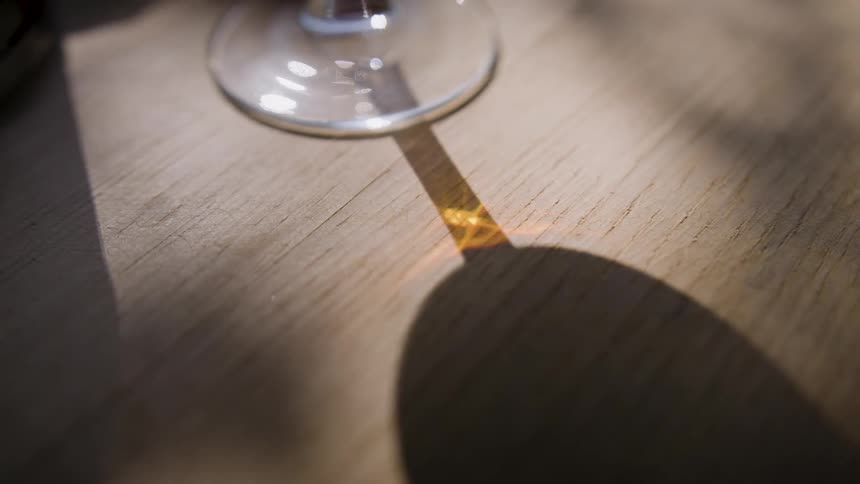 Light through glass causes a strange reflection on the shadow of a frying pan on a wooden table
