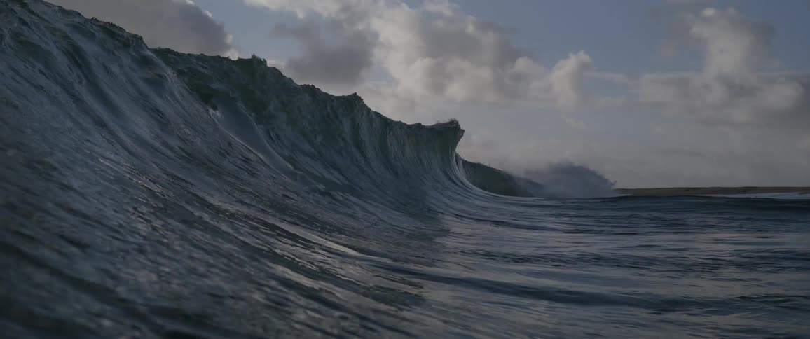 A large wave crashes in the ocean during the day