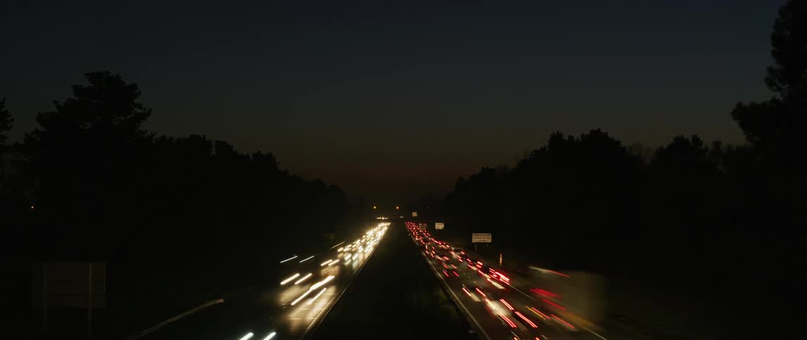 Hundreds of vehicles pass down a busy freeway at night