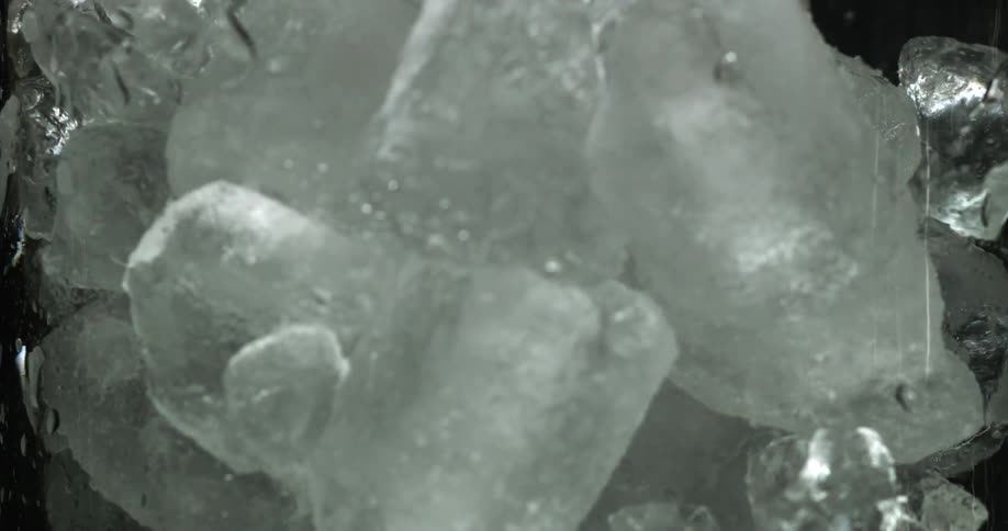 Ice cubes fill glass in dark area