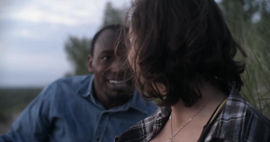 A man and woman sit on the ground and look upward