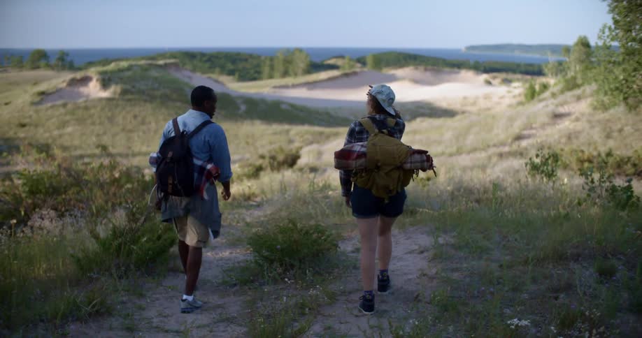 Two hikers walking towards a cliff in the morning