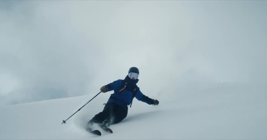 Skier skis down slope creating a cloud of snow