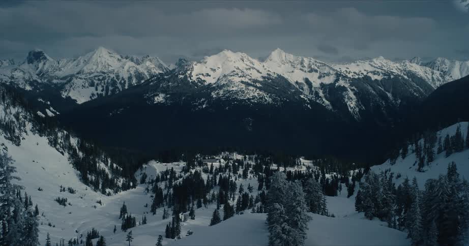 A snow capped mountain range in the countryside on a cloudy day