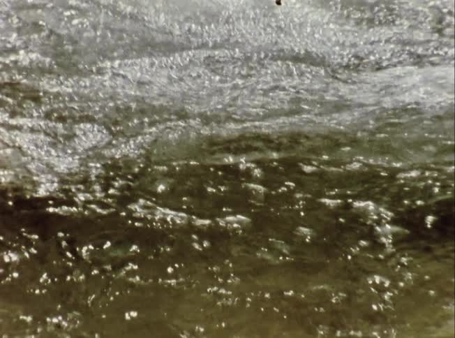 Water churns and foams as it rolls over sandy bottom