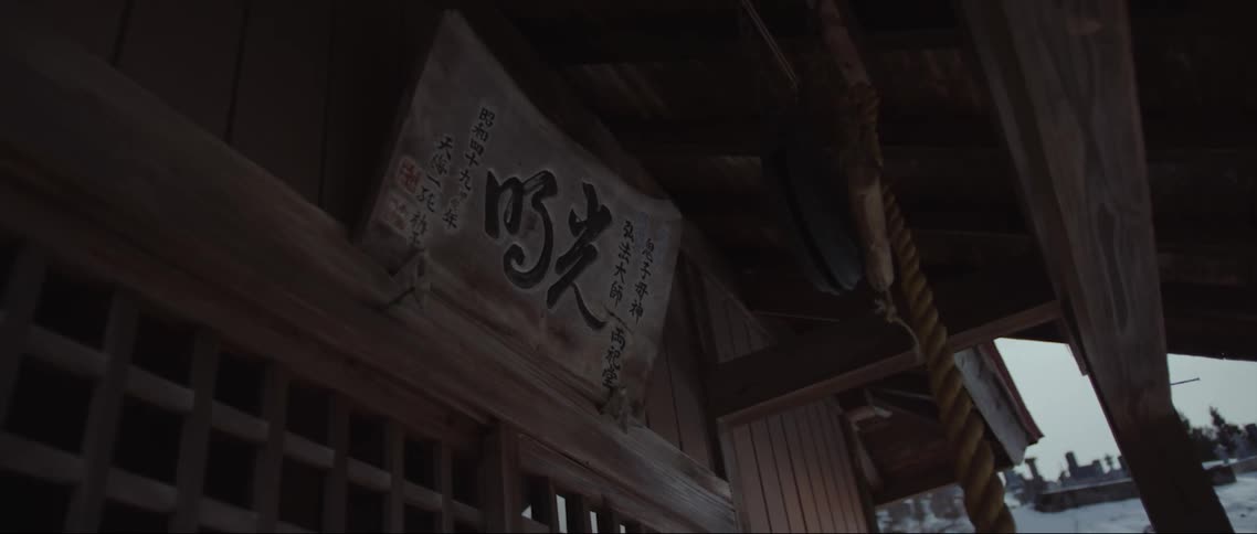 Sign of kanji characters sits over doorway in traditional wooden building