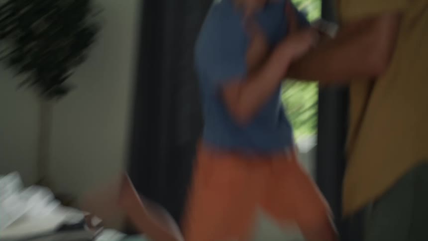 A little boy is standing on a bed and he runs across the mattress and leaps into his mothers arms