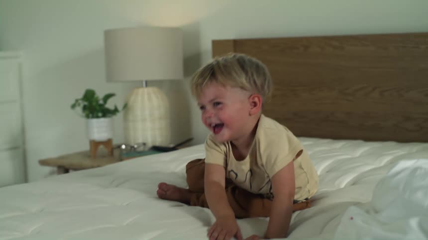 Two children laughing and playing on a bed