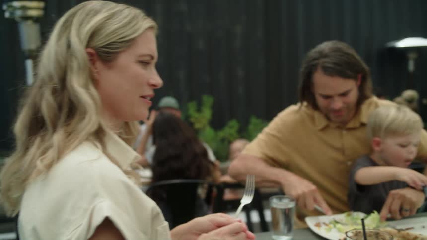 A mother and father with two young sons dining on an outdoor restaurant patio