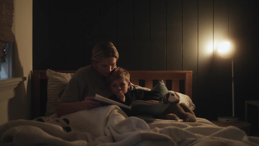 Woman sits in bed with her son reading him a bedtime story