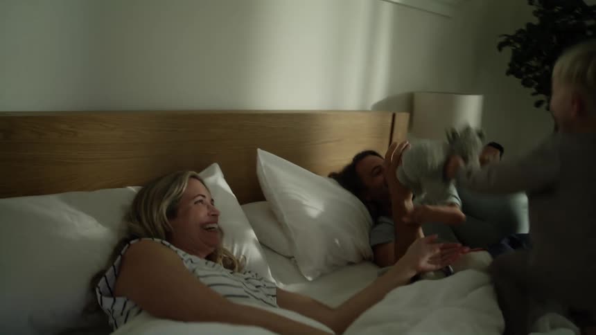 Two young sons running into their parents bedroom and jumping into their bed to wake them