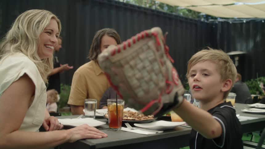 Young boy having lunch with family at a restaurant tries a baseball glove
