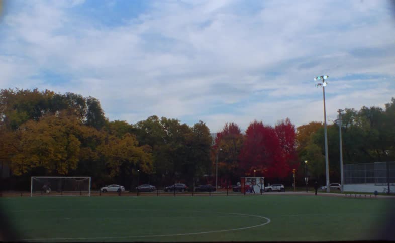 A soccer field in the fall with people around the field