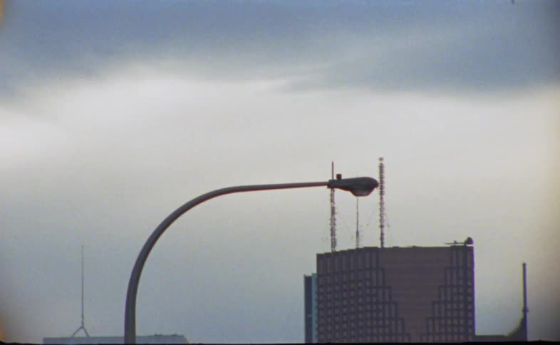 Airplane flies through cloudy sky above downtown skyscrapers