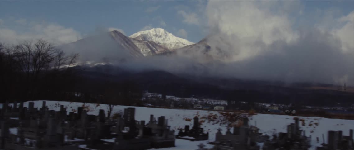 A large cemetery near a cloudy sky and mountains
