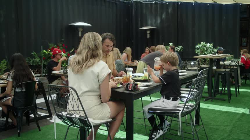 A man pulls his son down from climbing on the table in a restaurant