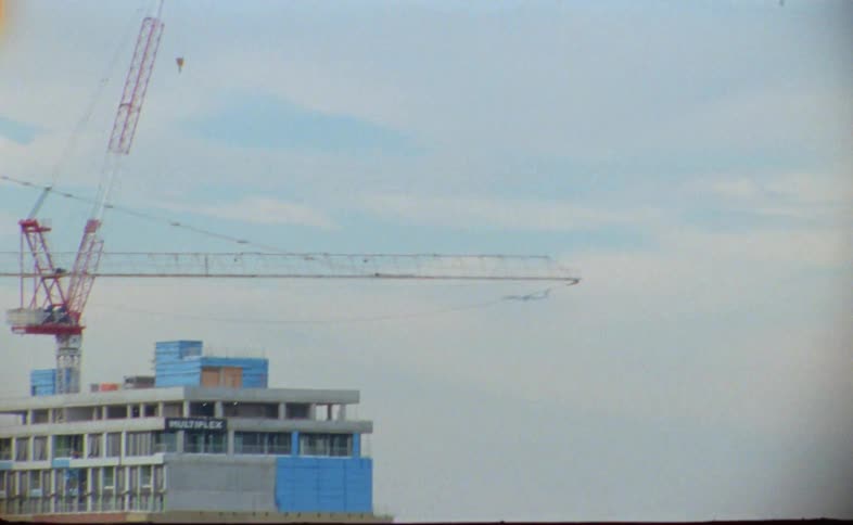 Airliner flies past building under construction near intersection