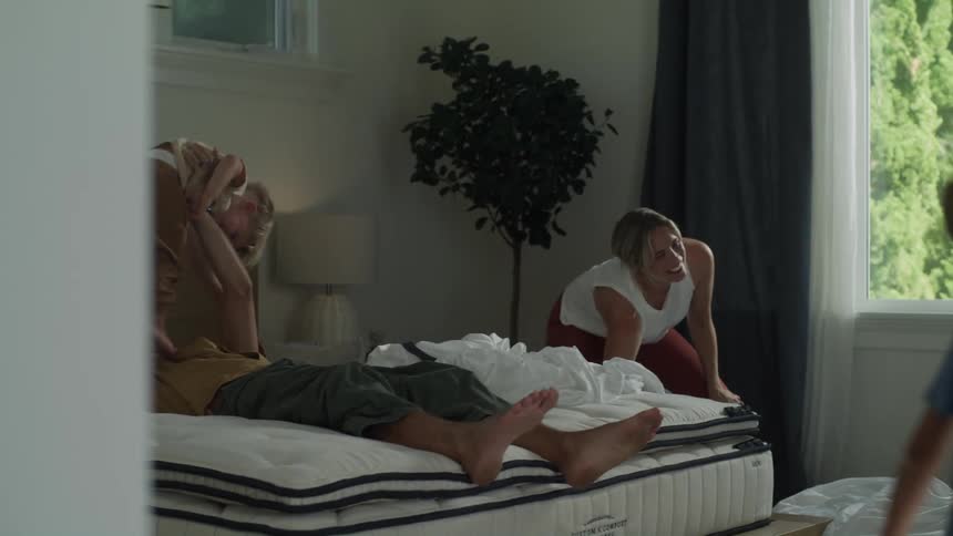 A family of four playing in the bedroommom using pillows