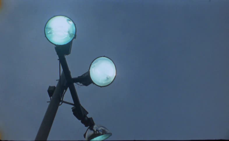 Outdoor light pole with three spot lights glow under overcast sky