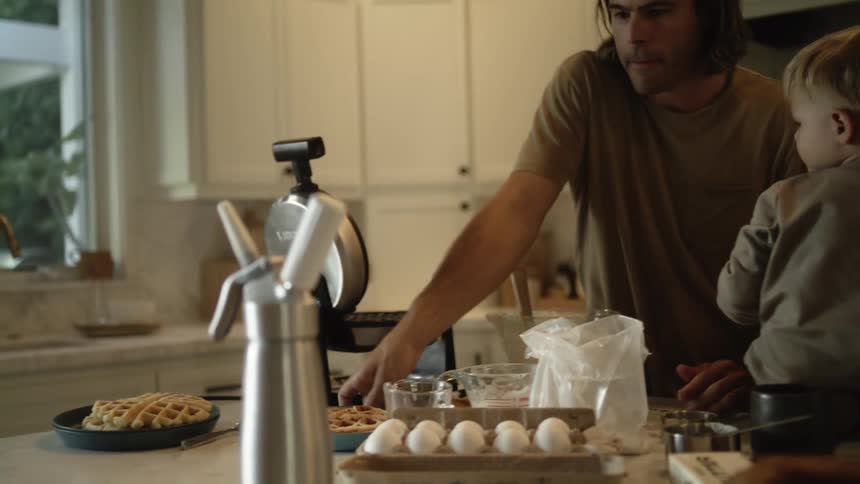 A man makes waffles at home for his sons