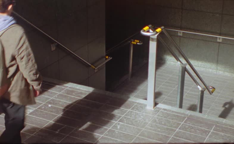 Shadows of people move on the floor as they walk down the stairs of a subway