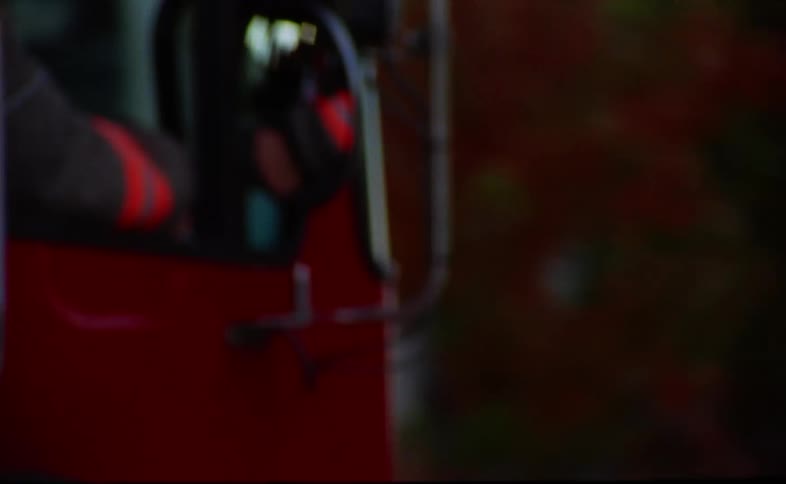 A firetruck with lights flashing driving down the road