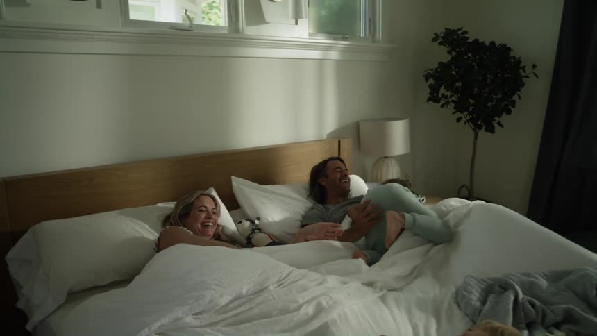 Kids jump onto bed where parents are lying