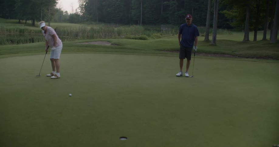A woman puts to the hole in golf and misses