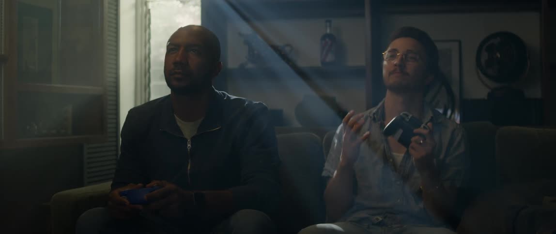 Two men sit on the couch playing video games together