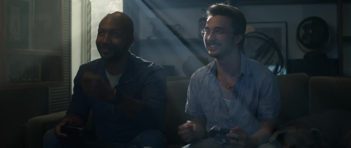 Two happy adult friends playing video games while sitting on the couch in the living room