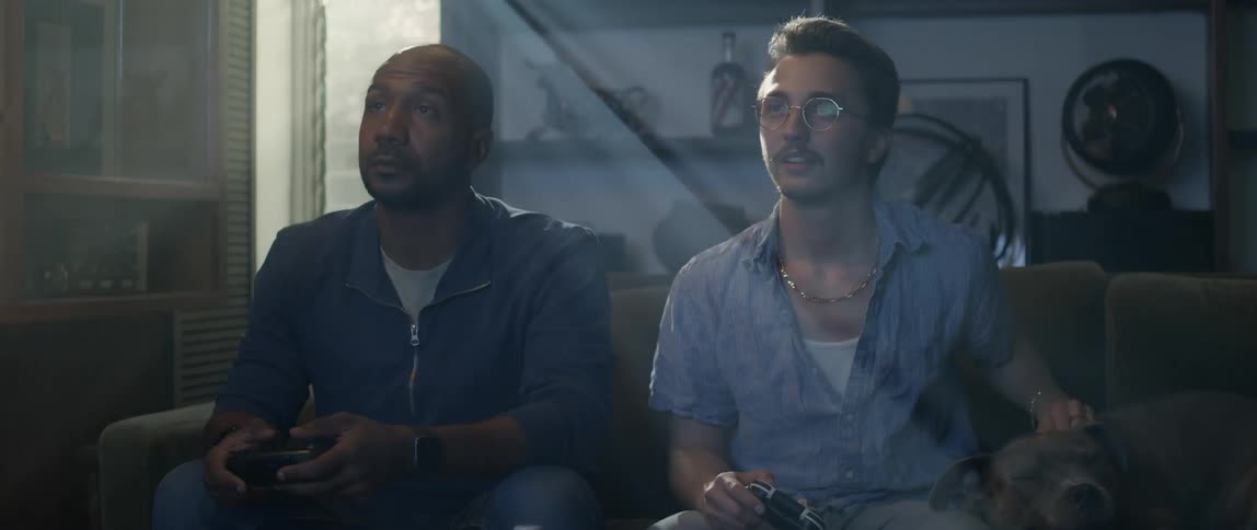 Two happy adult friends playing video games while sitting on the couch in the living room