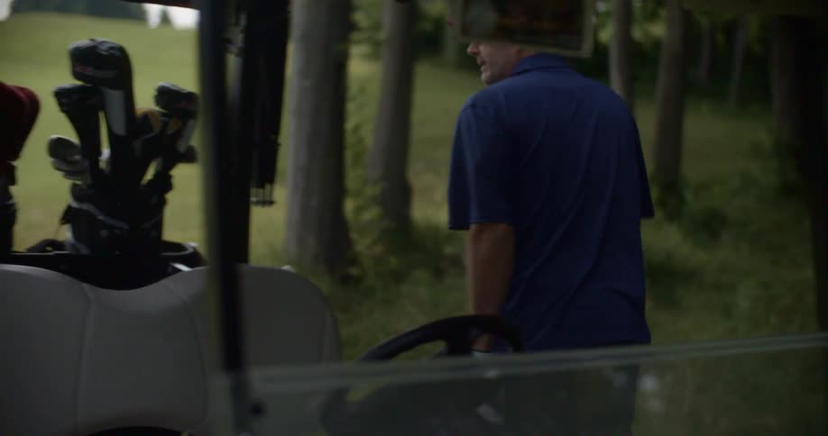 A man and woman get off a golf cart and retrieve their clubs from the back