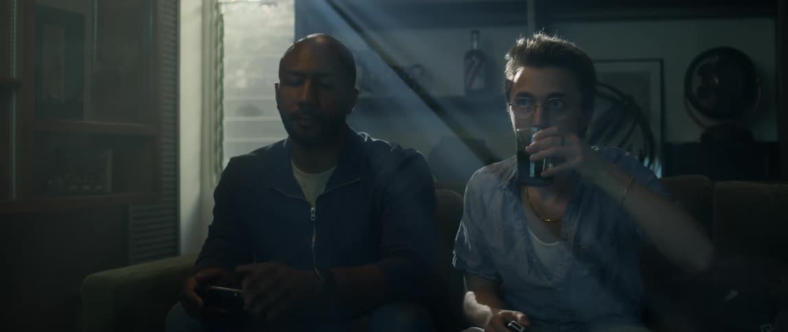 Two men play video games together and drink