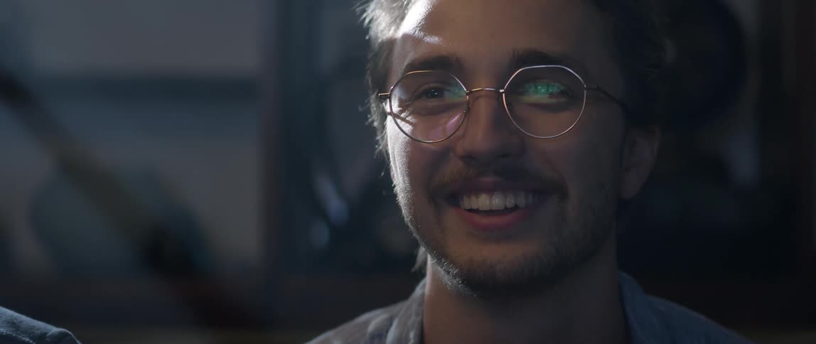 Man with glasses and beard plays video game laughing