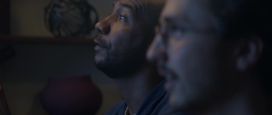 Two male friends watch show together and cheer
