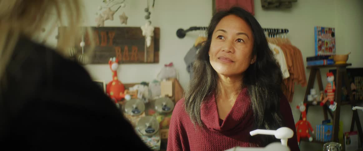An asian women shop owner speaks to a customer with blonde hair and listens to what they have to say