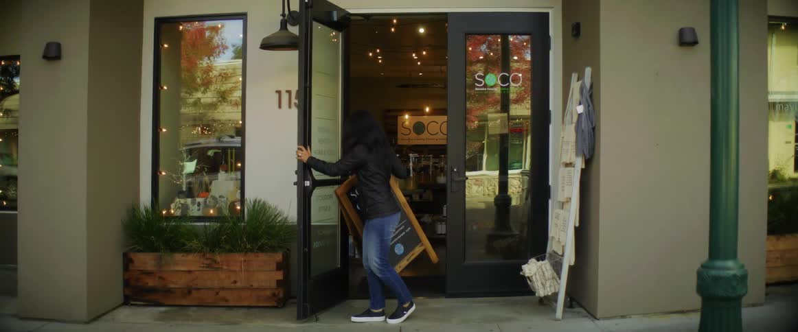 A woman puts a chalkboard easel sign outside her business