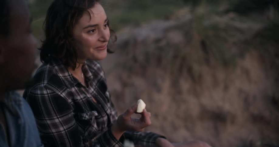 A man and woman talk and laugh while on a picnic in the evening