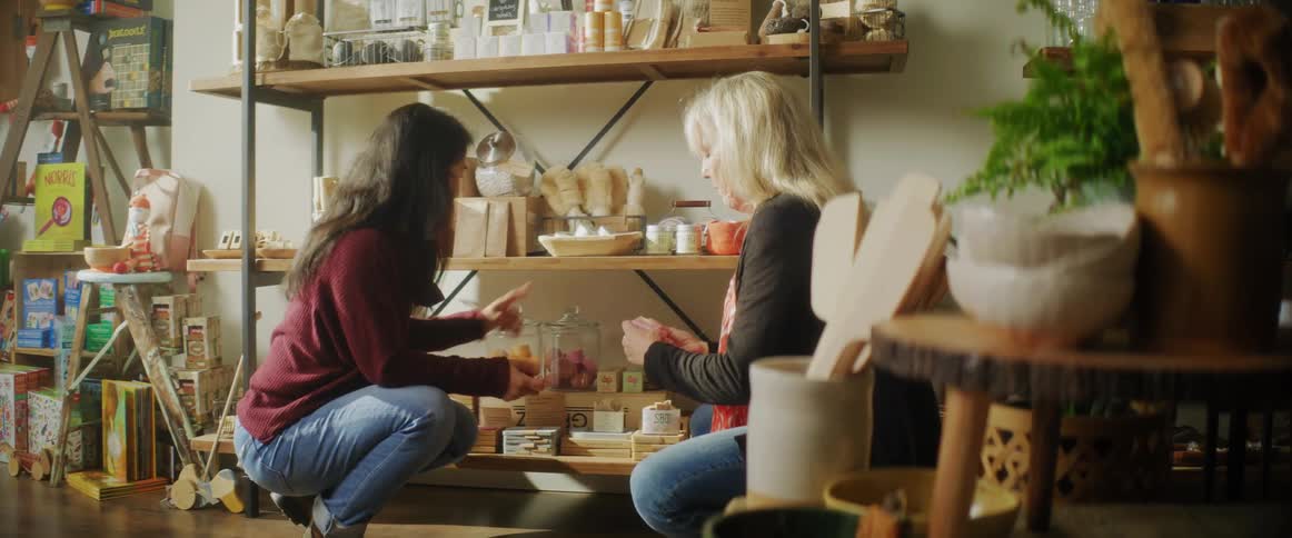 Two women are hanging out indoors and are sitting down