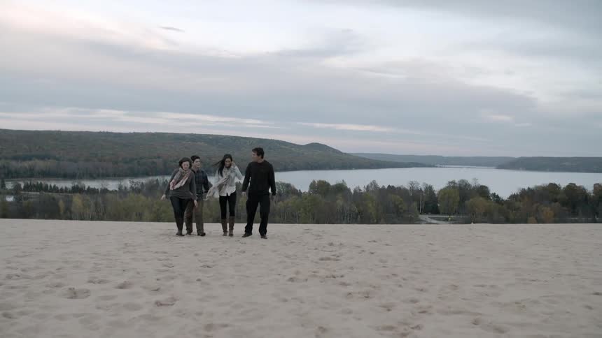 A group of people walk across sand