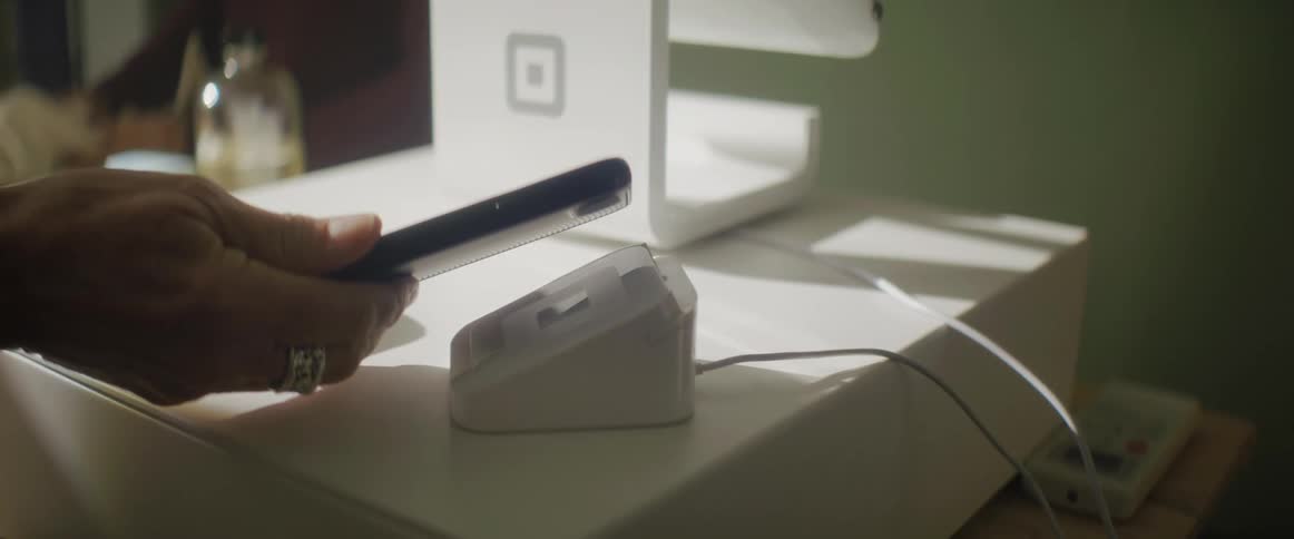 A person holds their cell phone to a charger