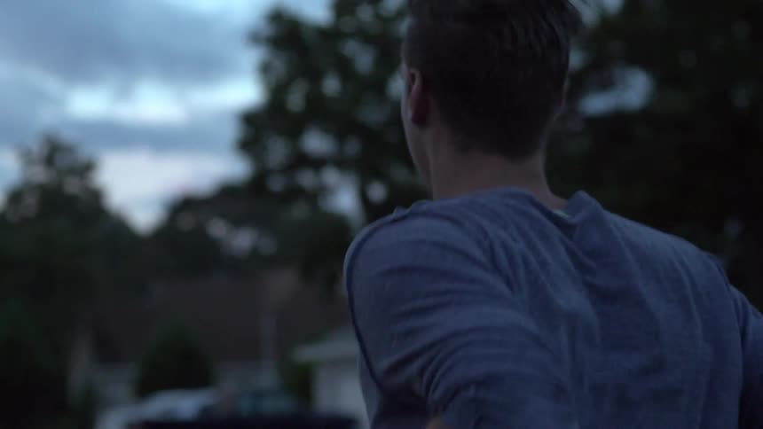 A man jogs in a neighborhood in the evening